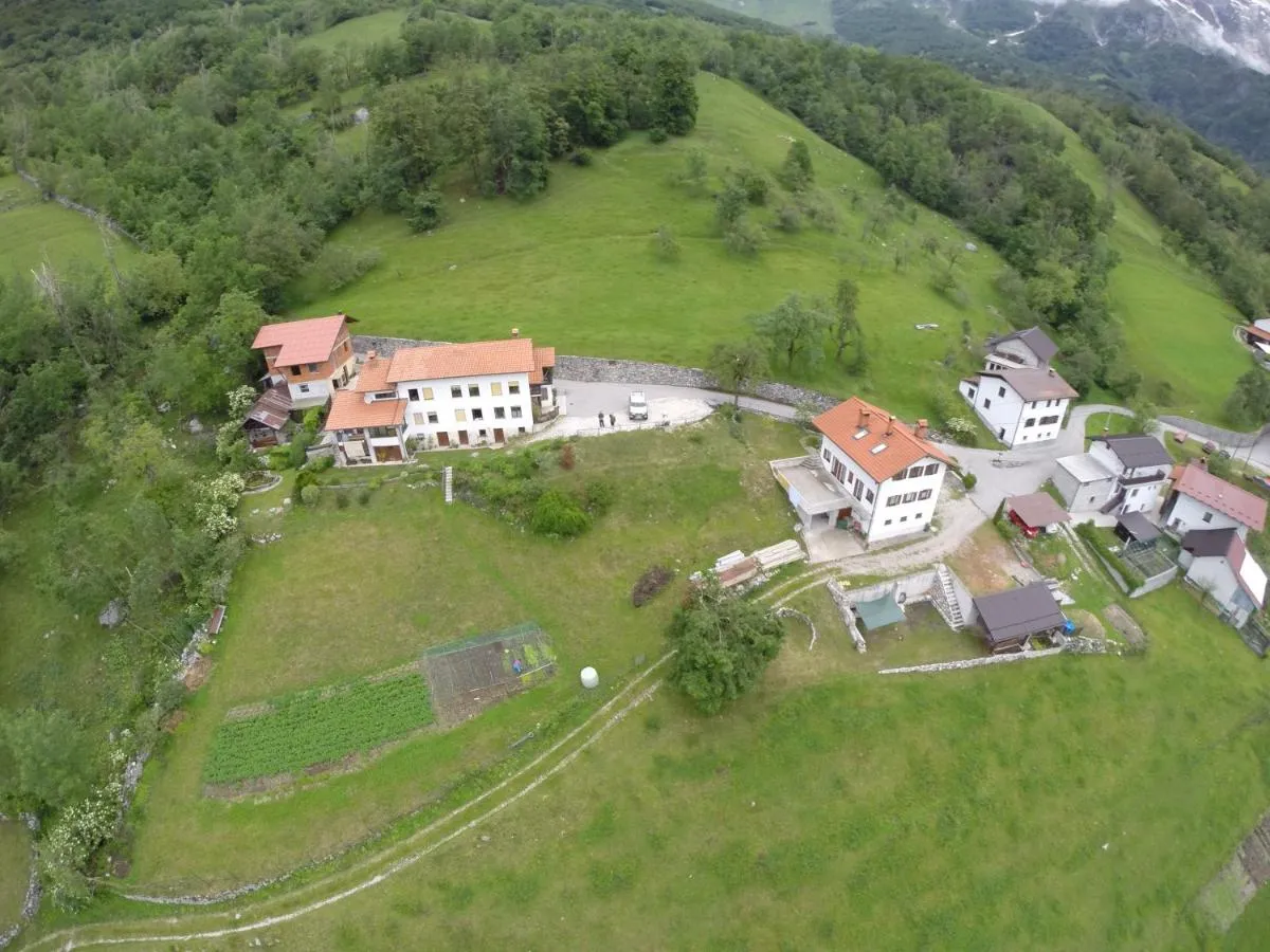 Pogled iz zraka: hiša na koncu vasi, travniki in cesta, ki se vije v dolino